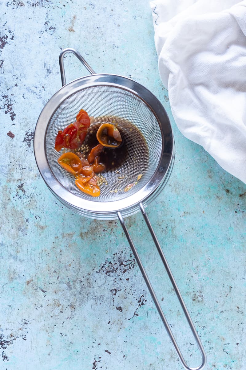 Tomato peels in a strainer set over a bowl