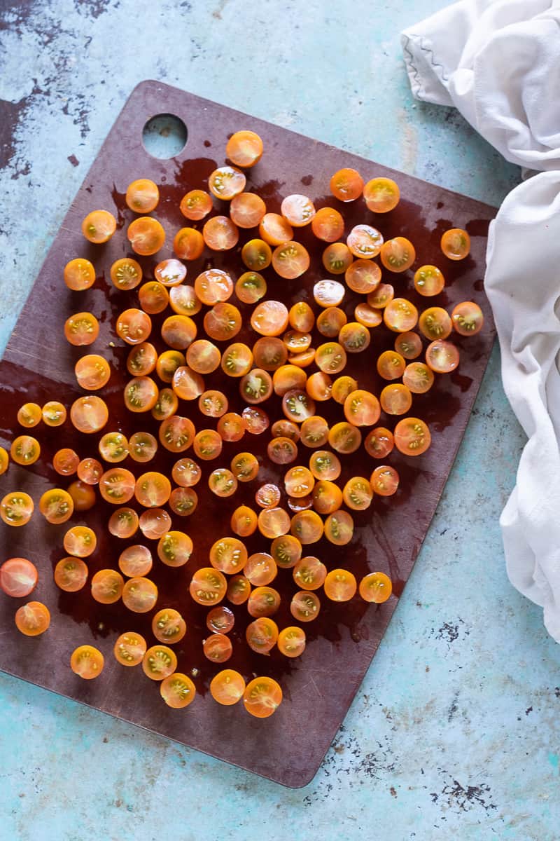 Sungold tomatoes sliced in half on a cutting board