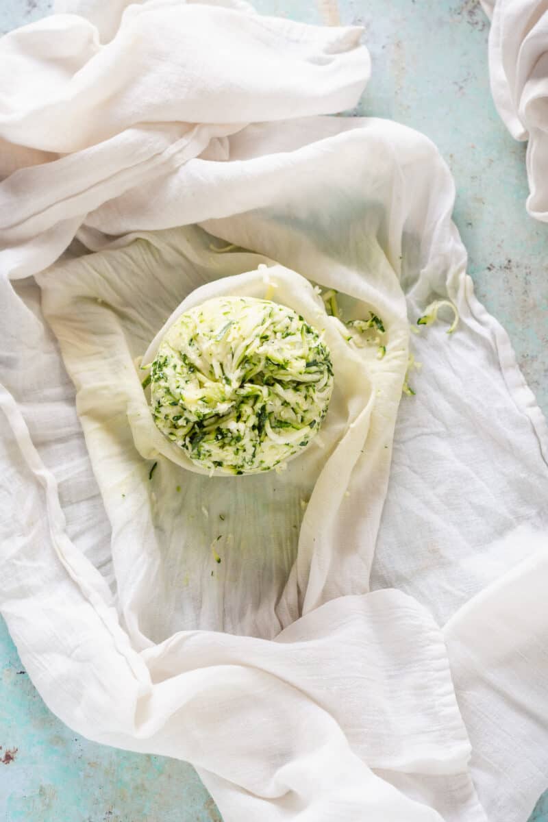 Ball of shredded zucchini on a tea towel after having the moisture squeezed out