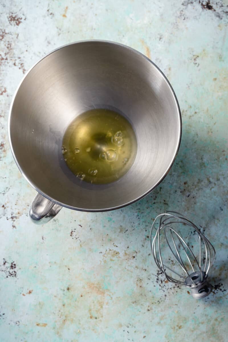 Egg whites in a stand mixer bowl with a whisk attachment alongside