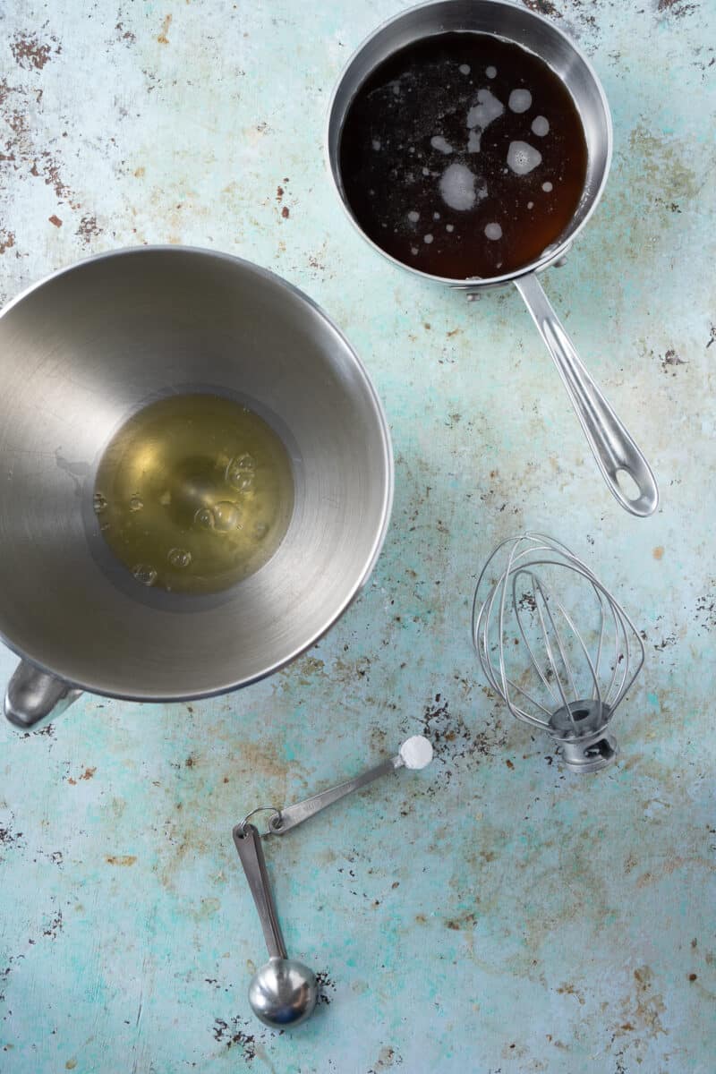 Meringue and sugar syrup in bowls, cream of tartar in a measuring spoon