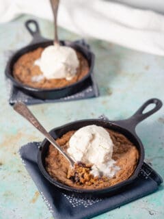 Two mini chocolate chip skillet cookies topped with vanilla ice cream