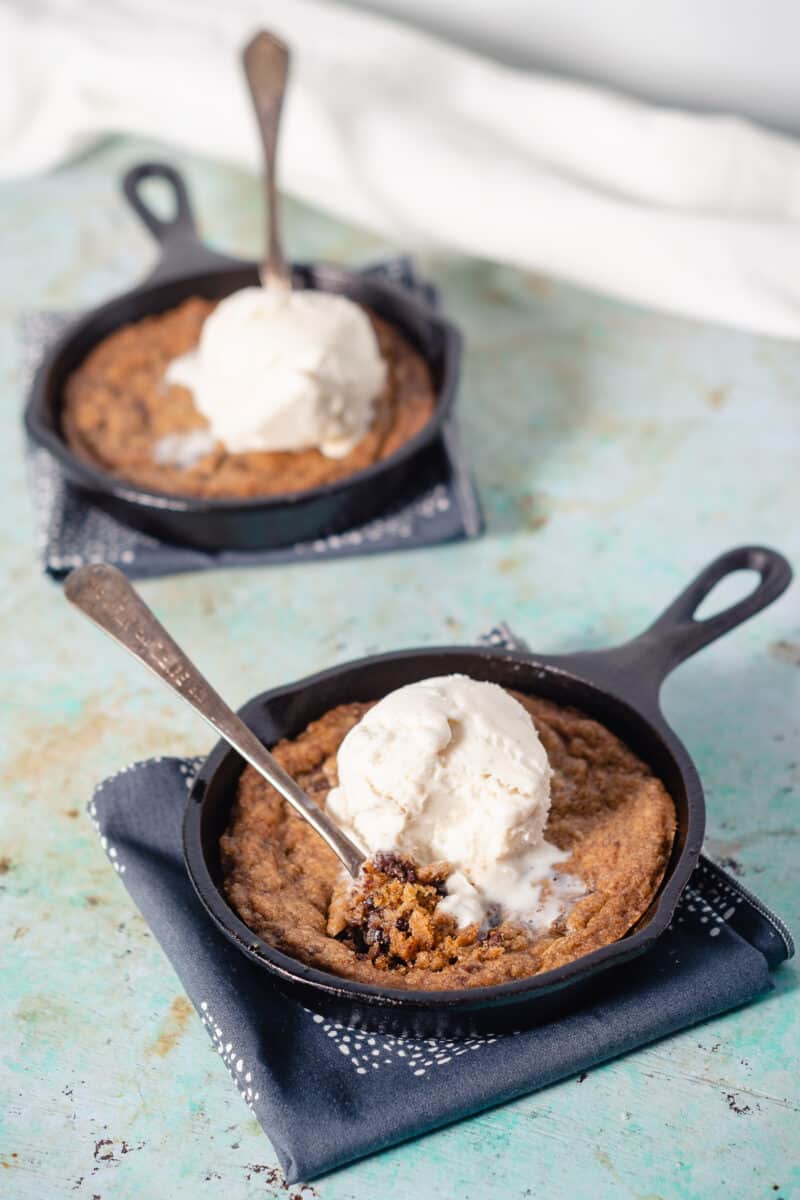 Two mini chocolate chip skillet cookies topped with vanilla ice cream