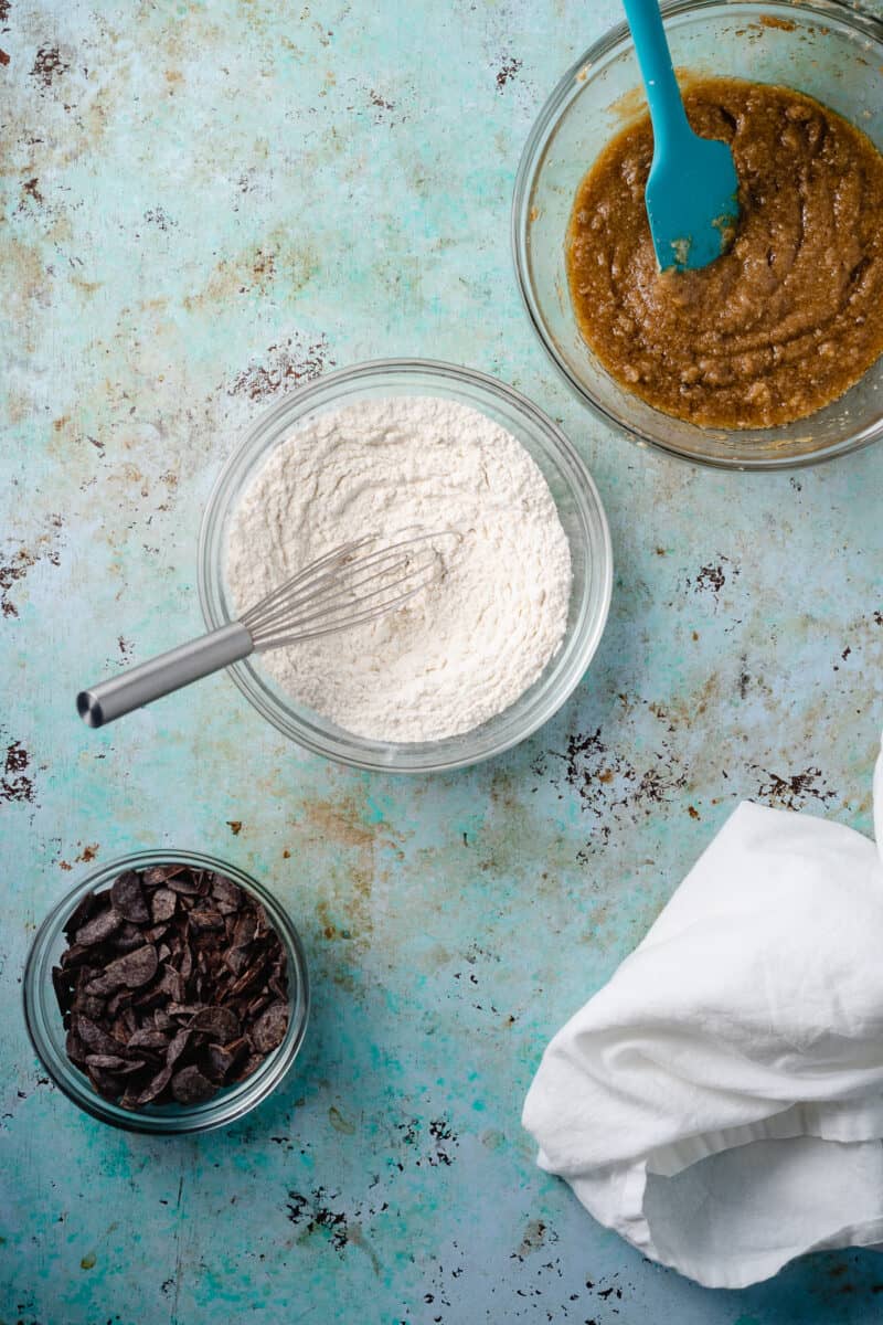 Bowls of wet ingredients, dry ingredients, and chocolate chips for cookie dough