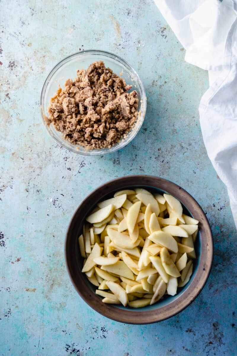 Apples and brown sugar in a baking dish with crisp topping in a separate bowl