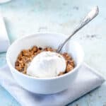 A bowl of apple crisp topped with vanilla ice cream