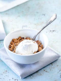 A bowl of apple crisp topped with vanilla ice cream