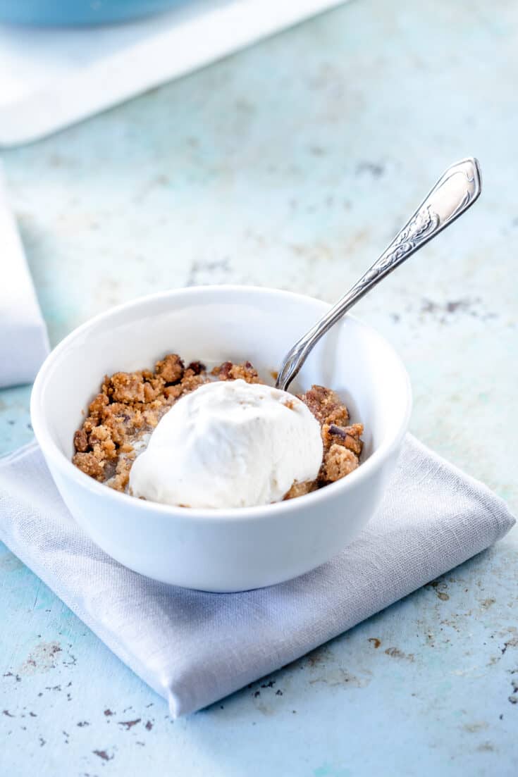 A bowl of apple crisp topped with vanilla ice cream