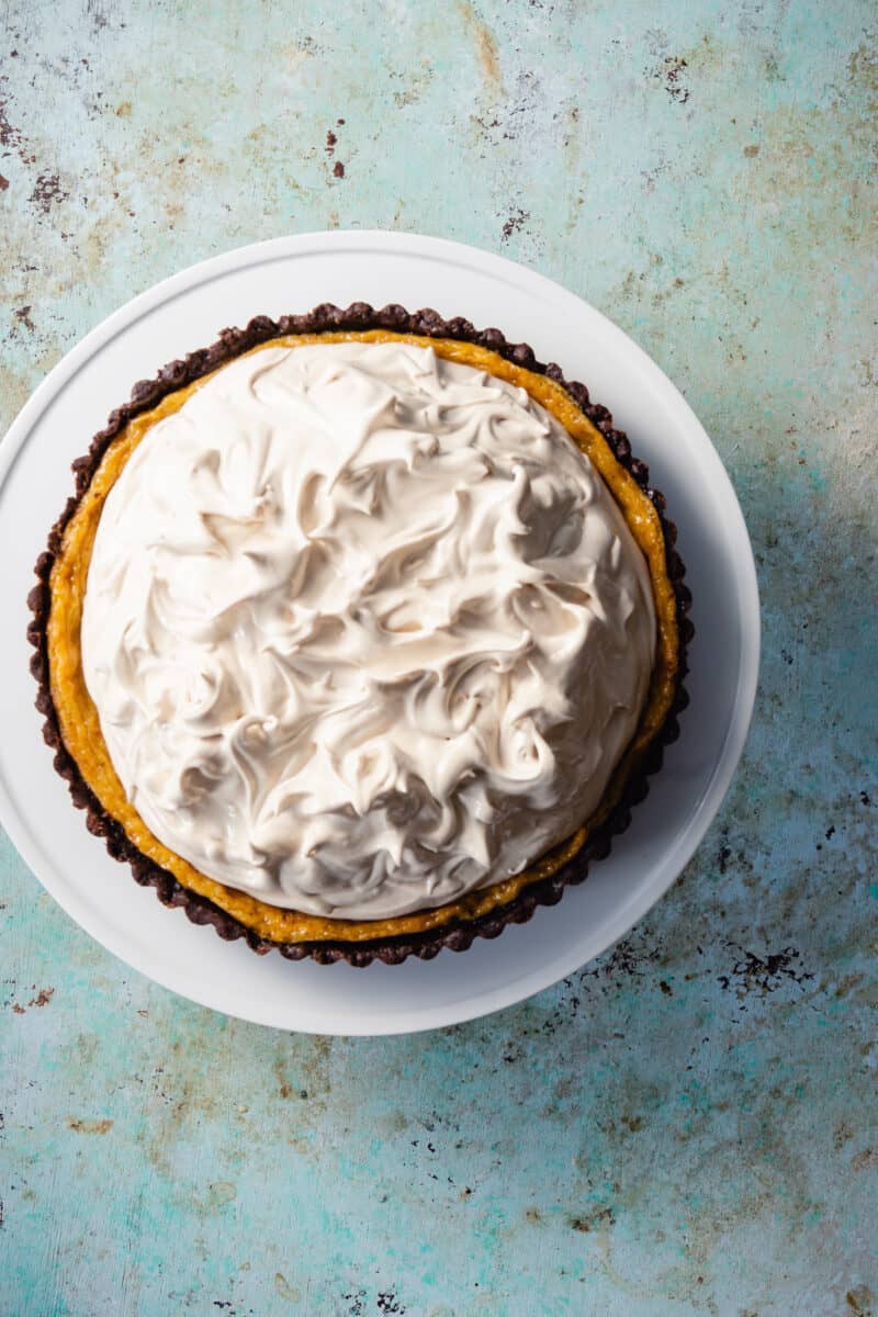 Banana Custard Tart with Brown Sugar Italian Meringue on a cake stand overhead view