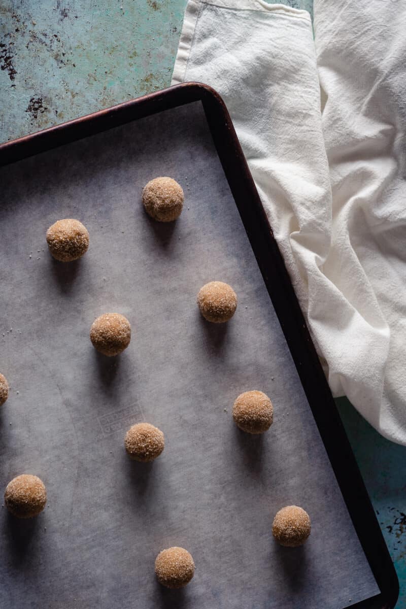 Balls of cookie dough coated in sugar on a baking sheet