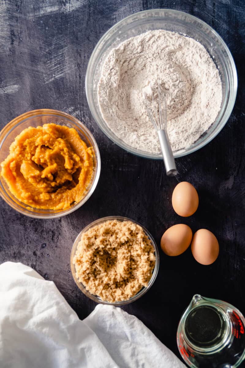 Flour mixture, pumpkin puree, brown sugar, three eggs, and a 1/2 cup of safflower oil in mixing bowls