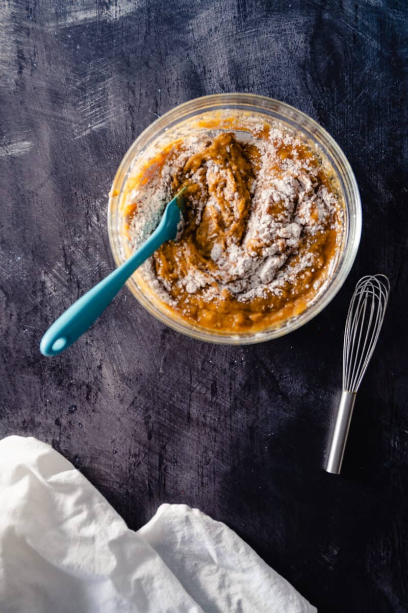 Pumpkin and flour mixture in a mixing bowl with a blue spatula