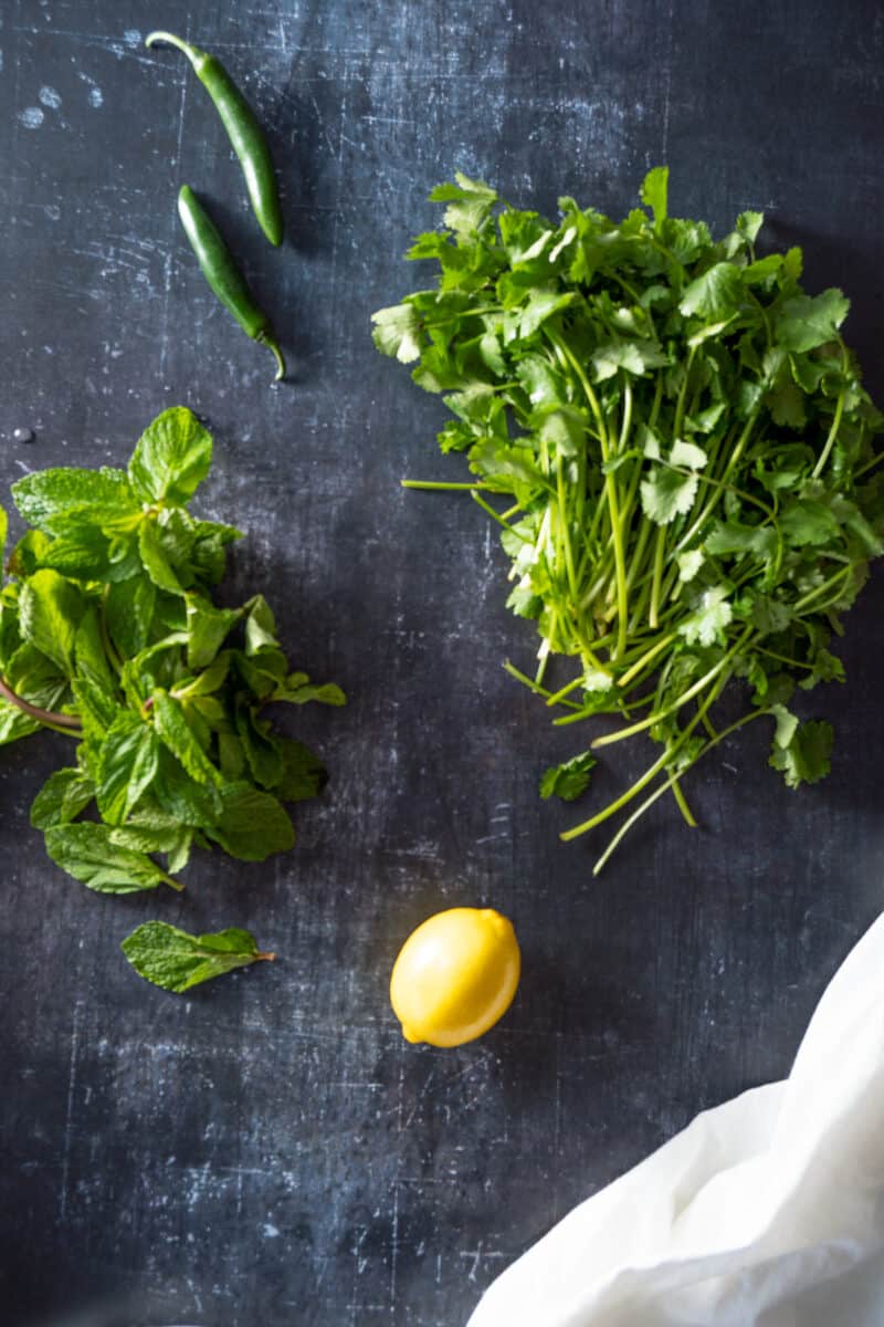 Mint, serrano peppers, cilantro, and lemon on a counter