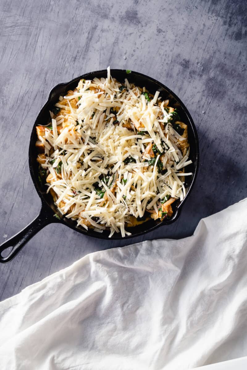 Unbaked chard and gruyere strata in a cast iron pan