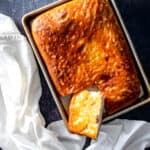 Focaccia in a sheet pan with a piece cut out showing the crisp bottom