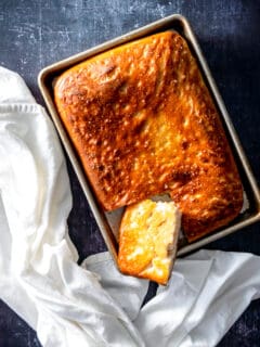 Focaccia in a sheet pan with a piece cut out showing the crisp bottom