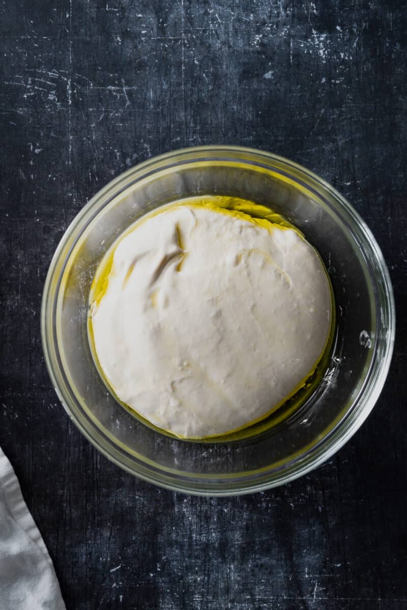 Focaccia dough in a glass mixing bowl with olive oil
