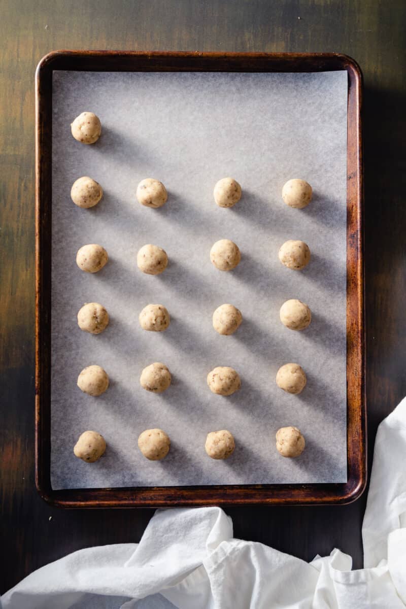 Cookie dough rolled into balls and arranged on a sheet pan