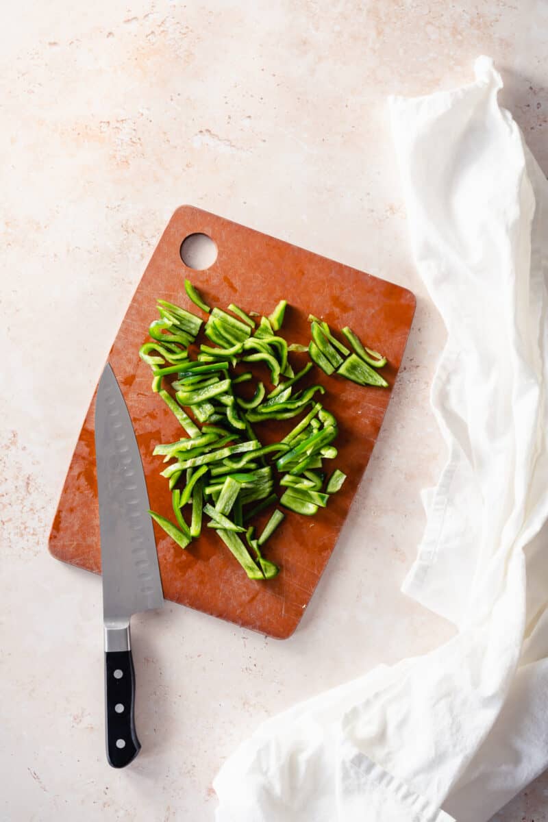 Sliced poblano peppers on a cutting board with a chef's knife