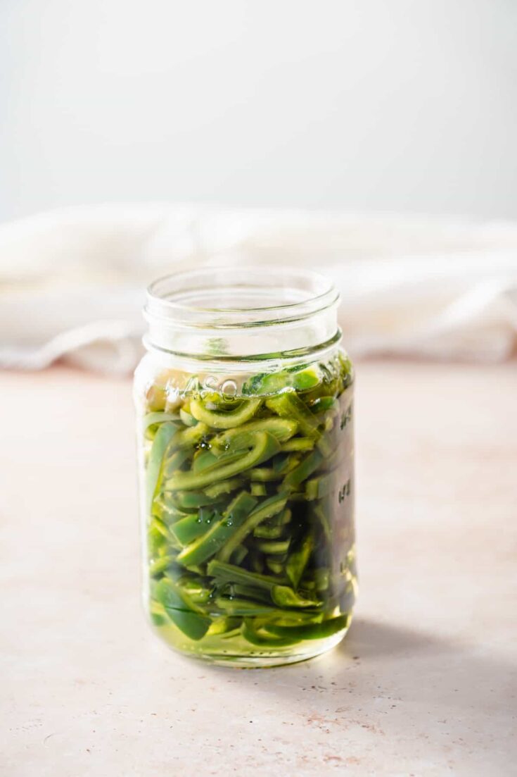 Quick pickled poblano peppers in a mason jar, side view