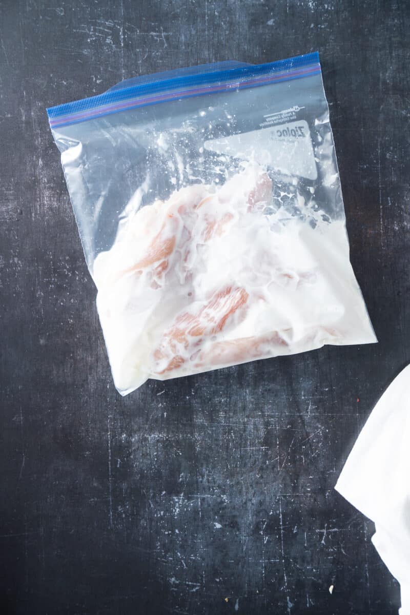 Chicken pieces in a buttermilk marinade in a zip-top bag