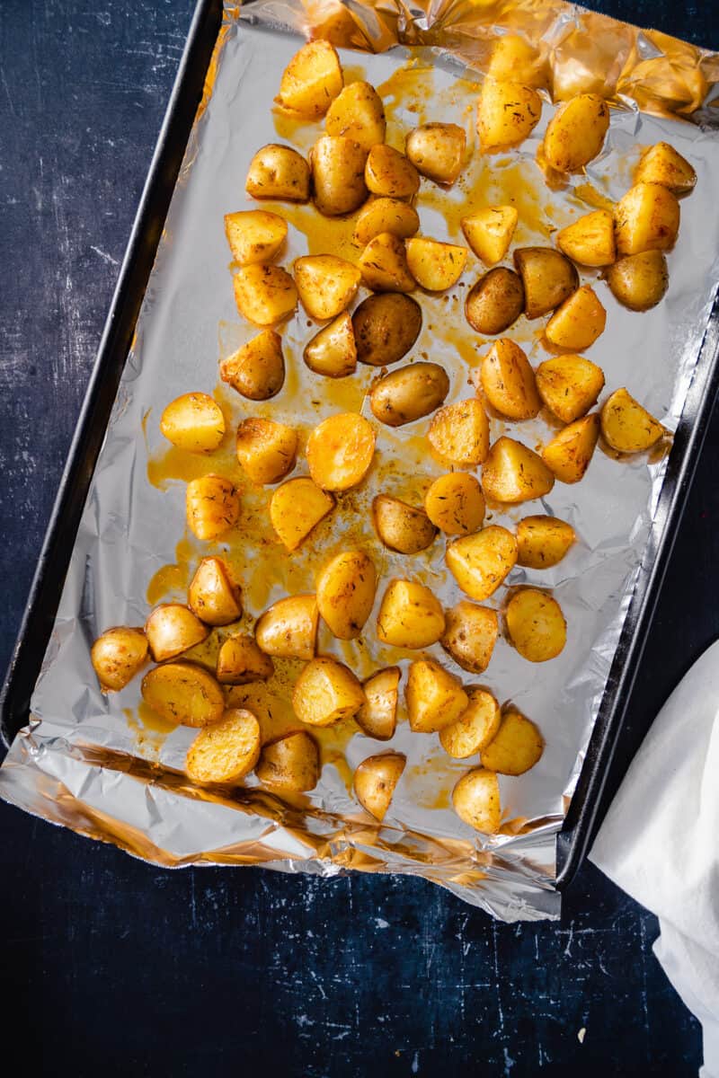 Oiled and seasoned potatoes on a foil-lined sheet pan