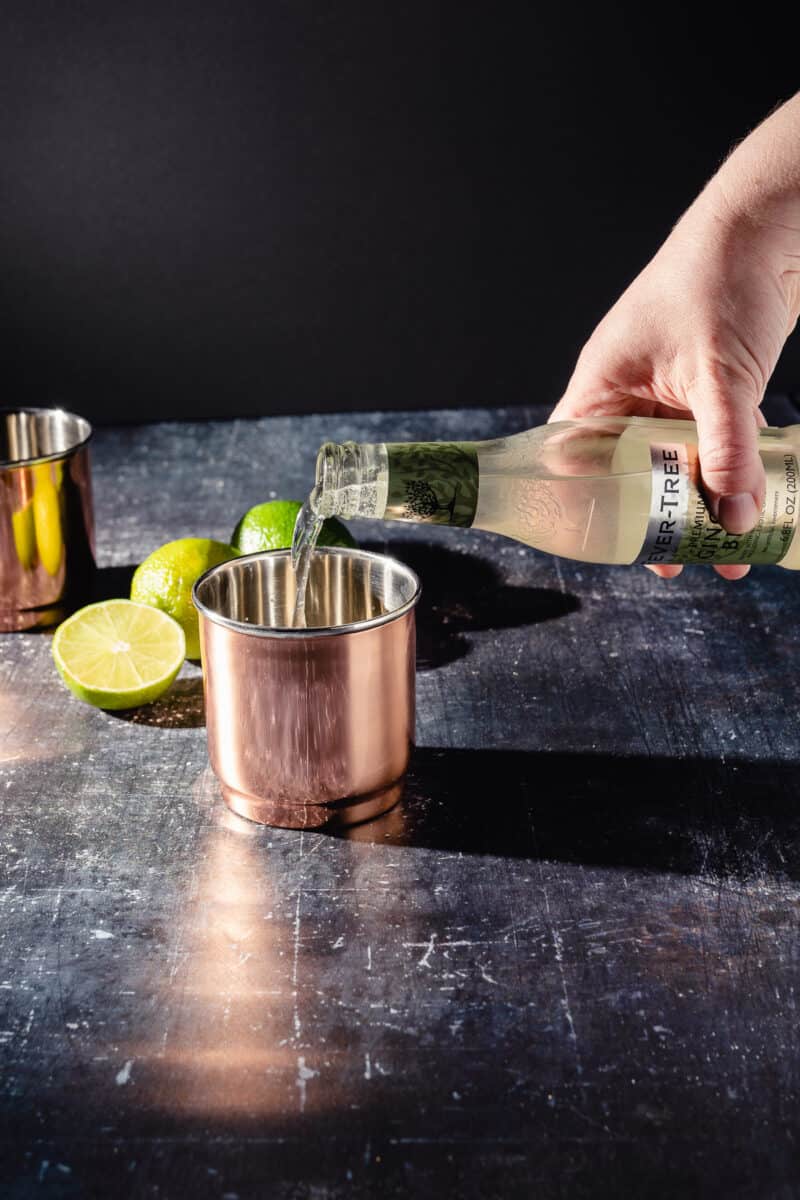 Ginger beer being poured into a copper cup to make a Moscow Mule