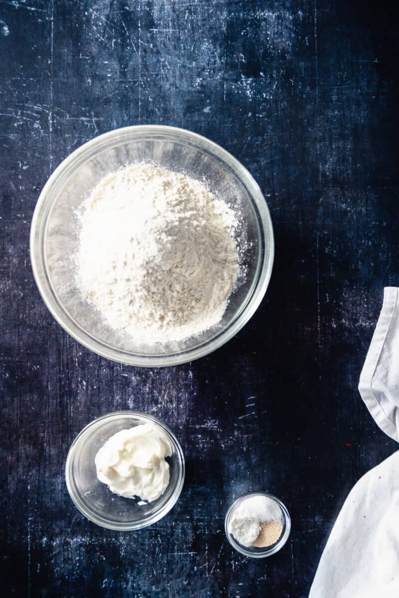 Flour, yogurt, baking powder, and yeast in mixing bowls