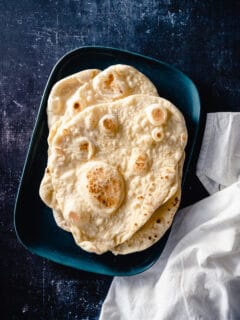 Four pieces on naan stacked on a blue tray