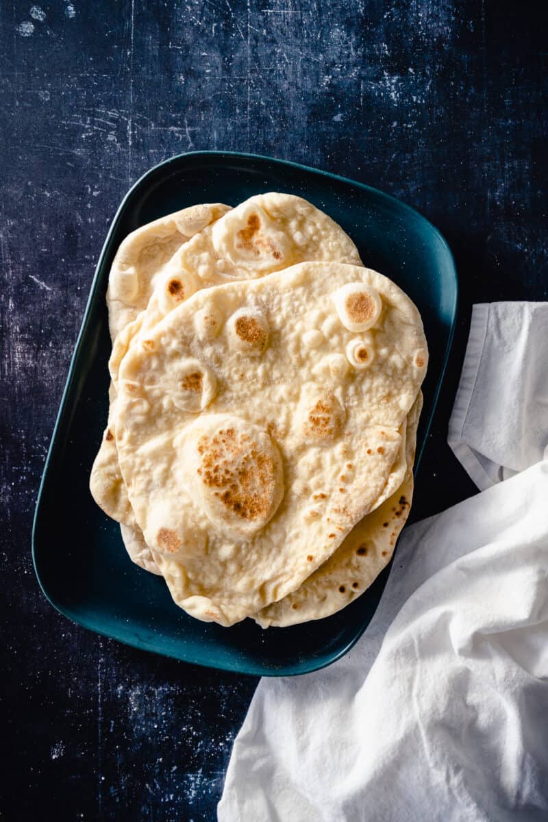 Four pieces on naan stacked on a blue tray