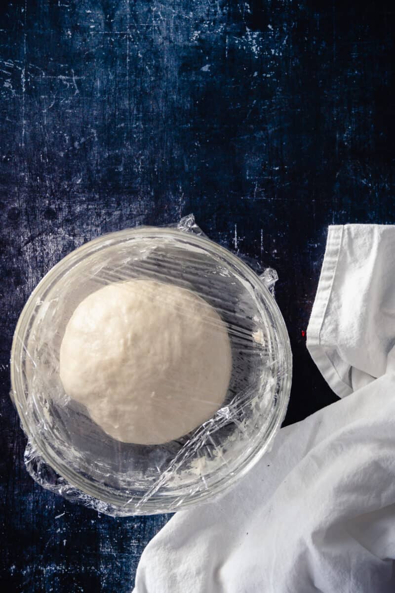 Naan dough covered with plastic wrap