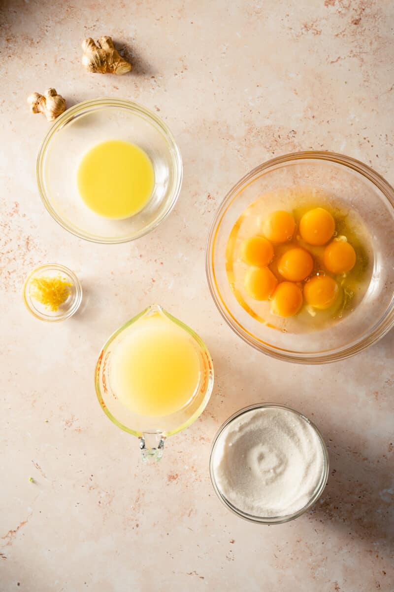 Ginger juice, eggs, sugar, lemon juice, and lemon zest in glass prep bowls