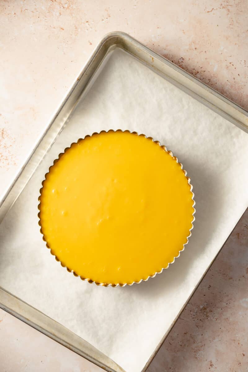 Lemon ginger curd poured into a baked tart crust on a sheet pan