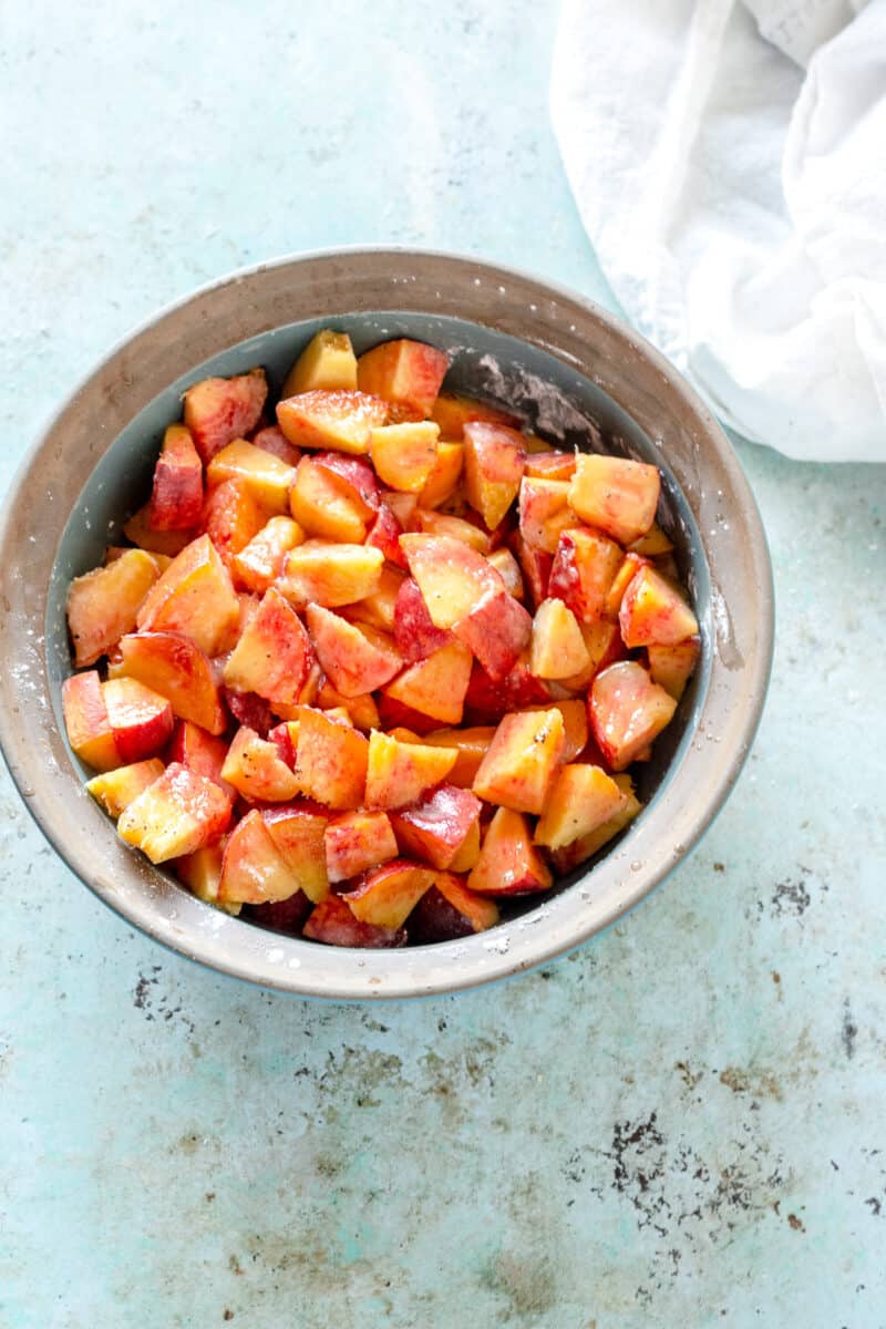 Overhead view of peaches mixed with sugar in a baking dish