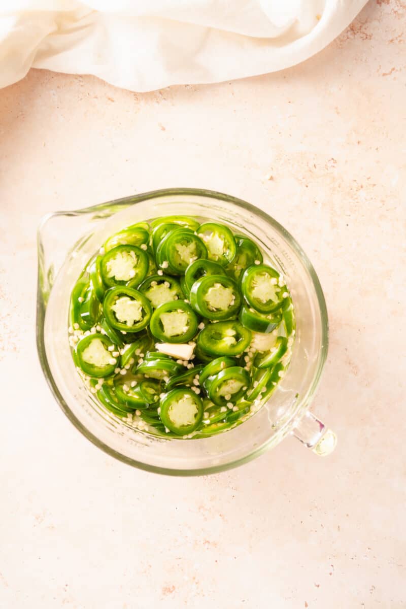 Sliced jalapeño peppers steeping in pickling brine