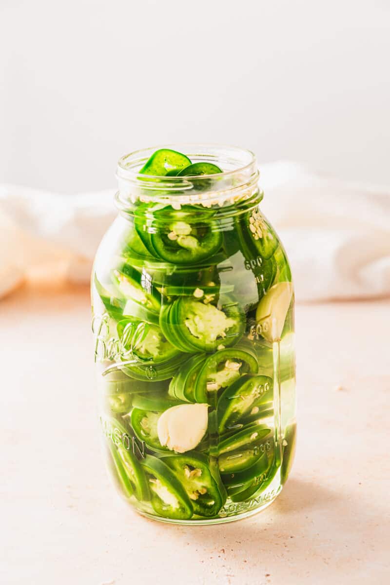 Pickled sliced jalapeños in a mason jar