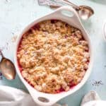 Rhubarb Crumble in a baking dish with two stalks of rhubarb alongside