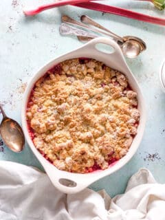 Rhubarb Crumble in a baking dish with two stalks of rhubarb alongside