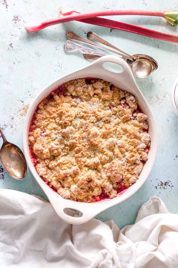 Rhubarb Crumble in a baking dish with two stalks of rhubarb alongside