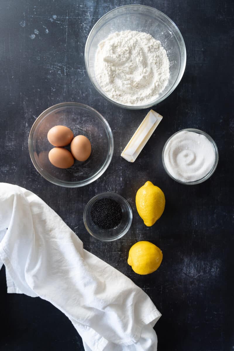 Flour, butter, sugar, lemons, poppy seeds, and eggs in prep bowls
