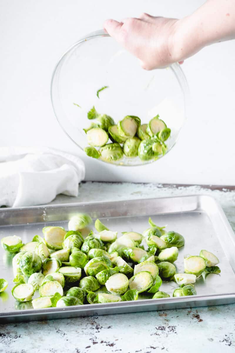 Brussels sprouts being added to a sheet pan