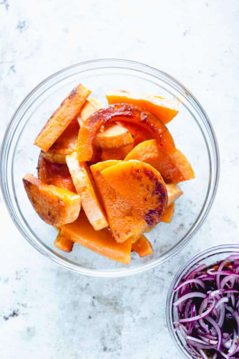 Roasted butternut squash slices in a bowl and pickled onions in agrodolce in a separate bowl