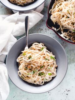 Ricotta walnut pasta in a gray pasta bowl with a pan of pasta alongside