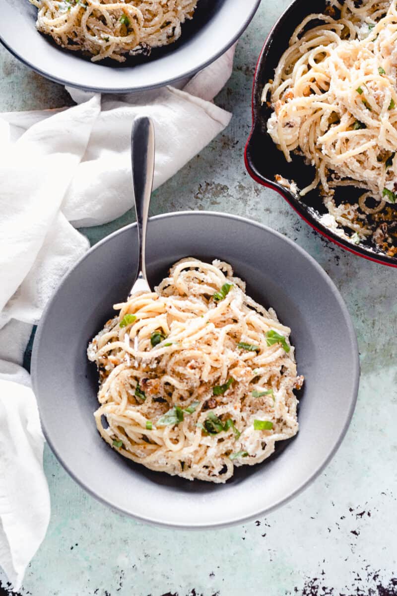 Ricotta walnut pasta in a gray pasta bowl with a pan of pasta alongside